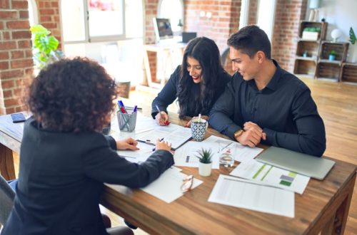 A couple sits at the desk in the lender's office as they review mortgage underwriting decisions with the lender.