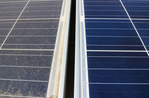 A dirty solar panel covered in dust, next to another clean solar panel with clear cells and connections under the sun.
